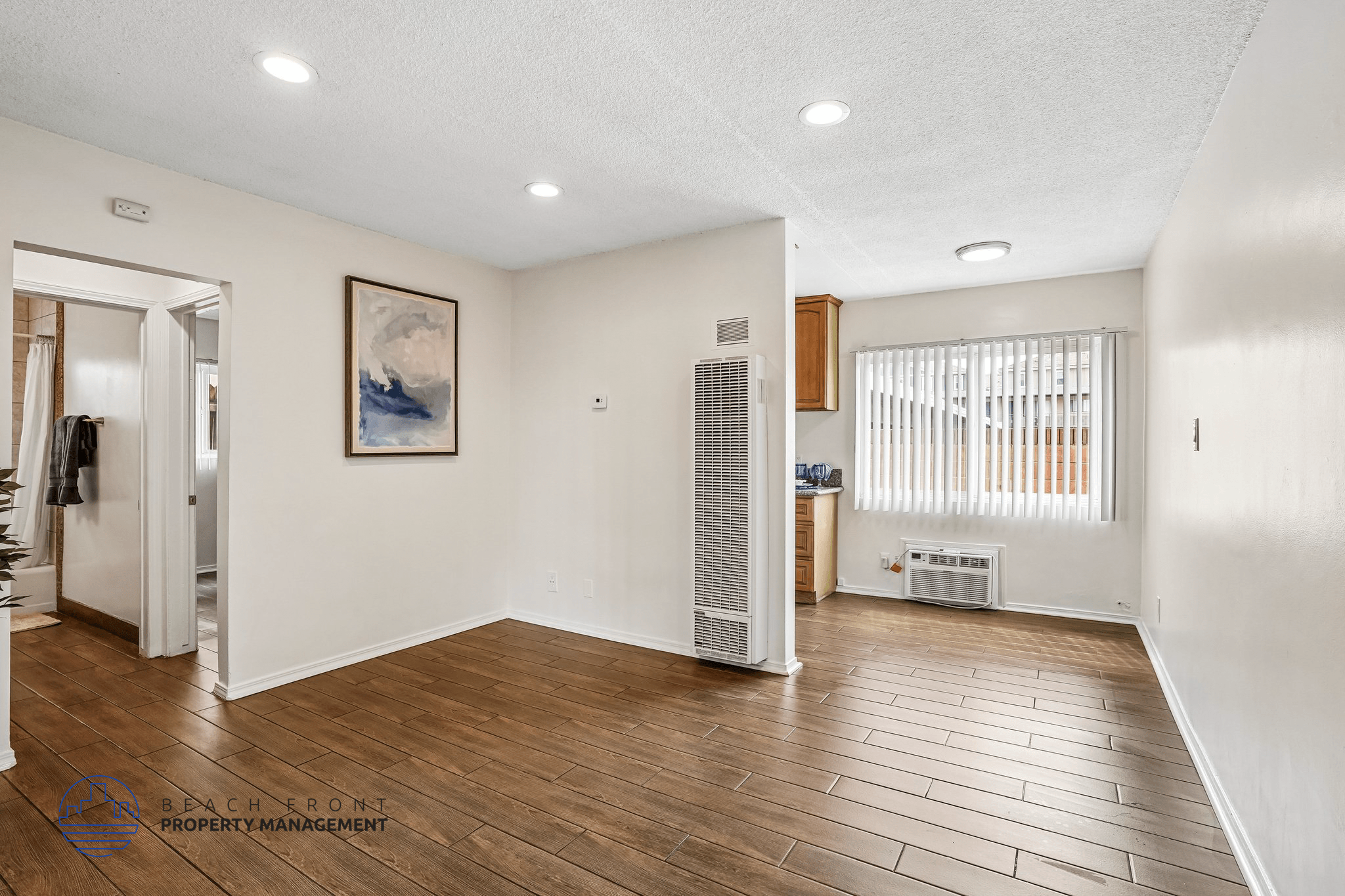 A room with a wooden floor and a painting on the wall.